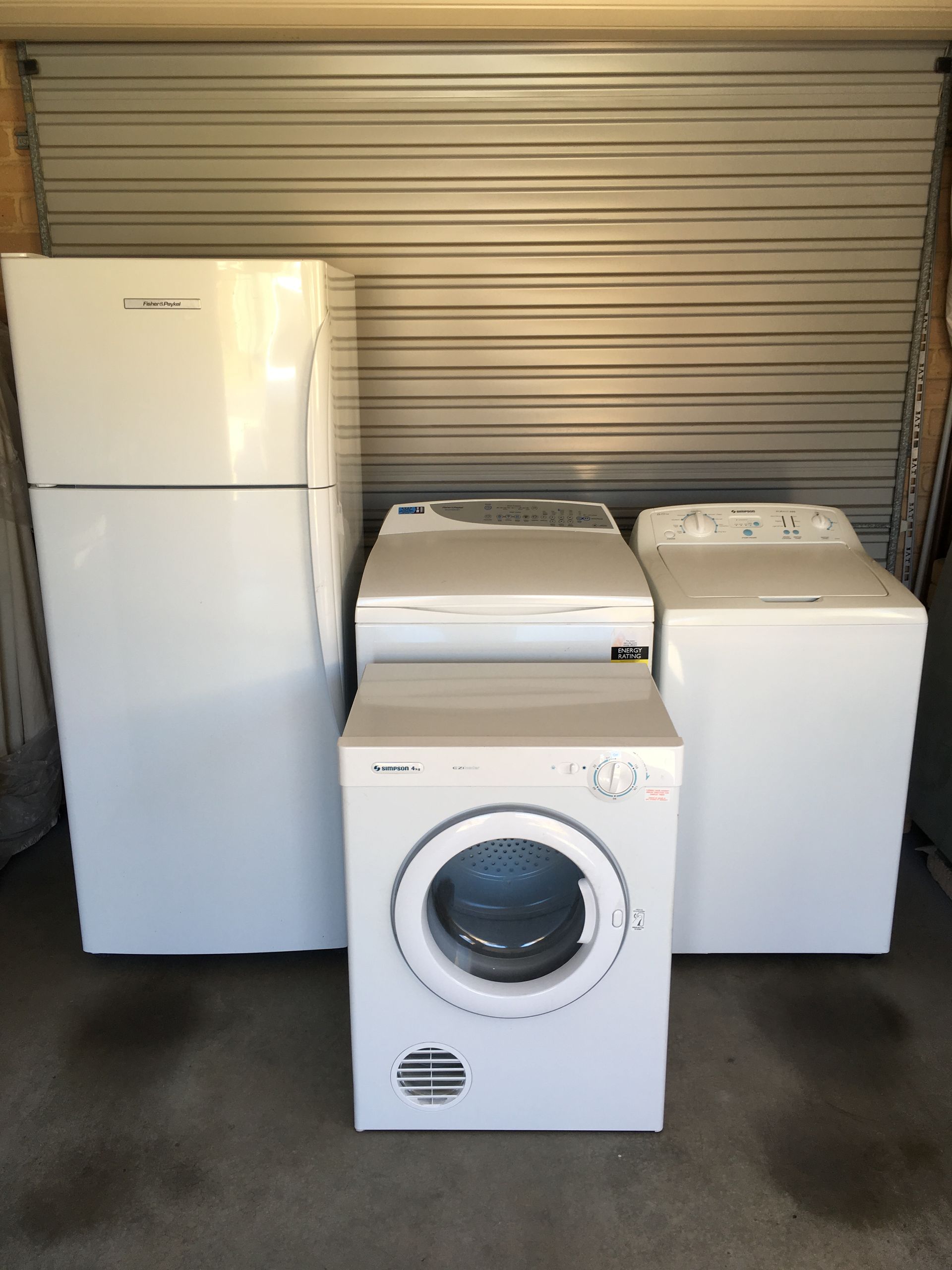 White refrigerator, washing machine, dryer, and top-load washing machine against a metal door — A.S.A.P. Appliance Service & Sales in Hamlyn Terrace, NSW