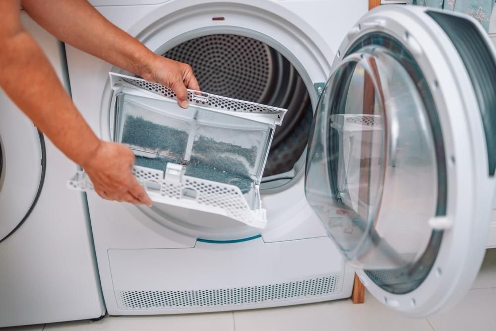 Person Removing Lint Filter from A White Dryer — A.S.A.P. Appliance Service & Sales in Wyong, NSW
