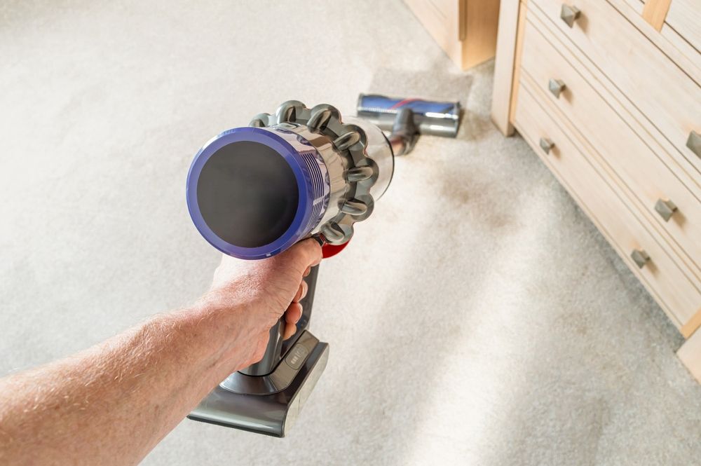 Hand Holding a Dyson Vacuum Cleaning Carpet — A.S.A.P. Appliance Service & Sales in Budgewoi, NSW