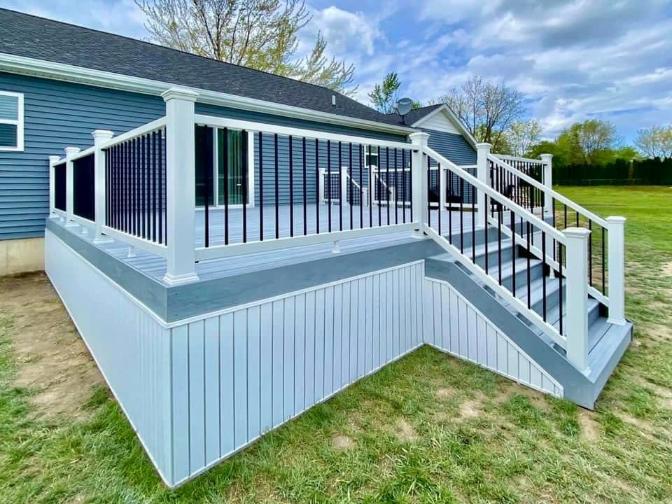 A blue house with a white deck and black railing.