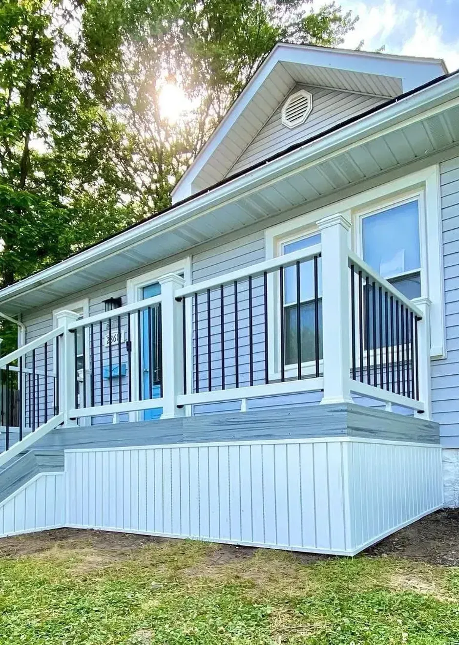 A wooden deck with a white railing and stairs next to a brick building.