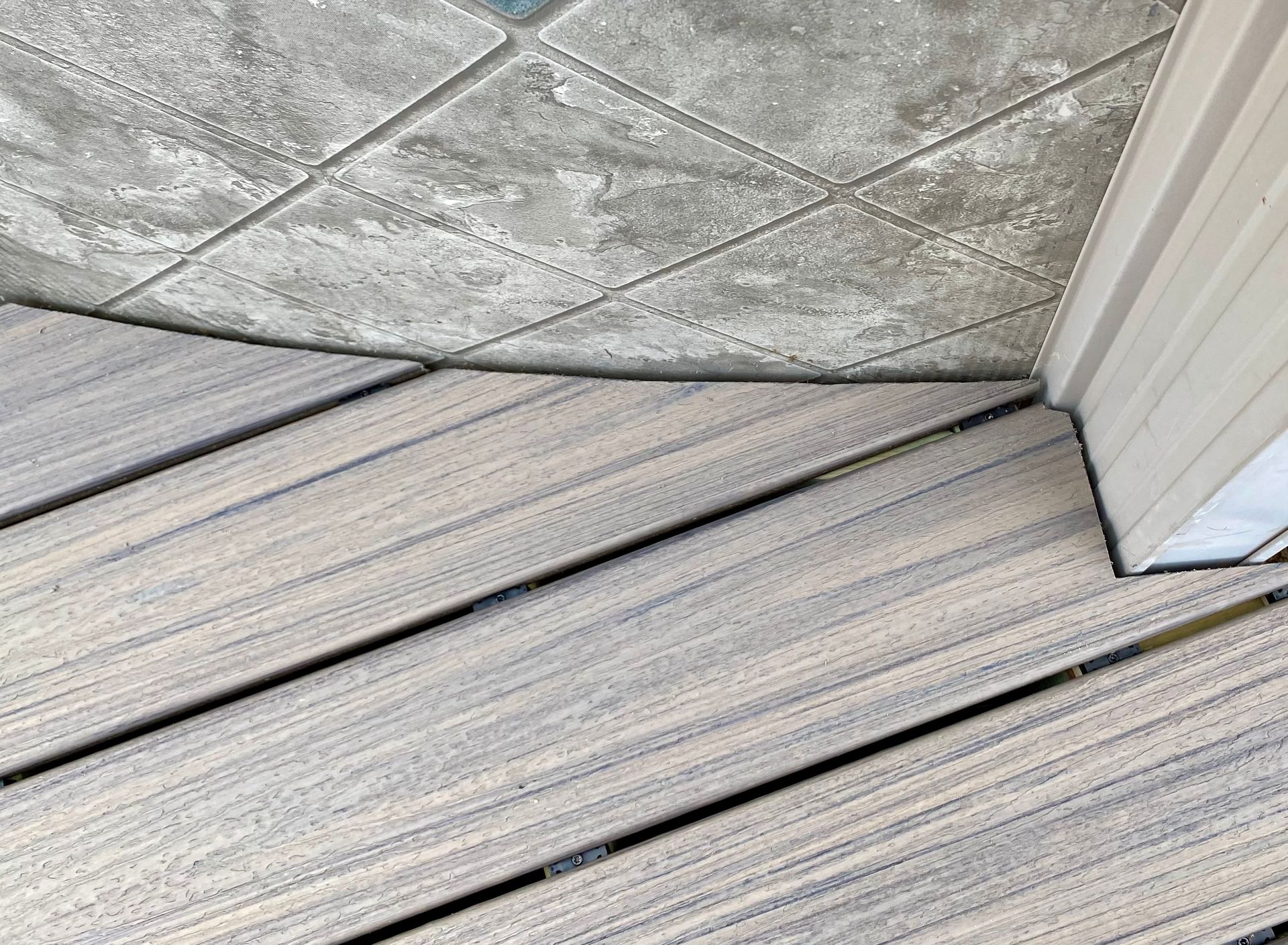 Beige slatted deck with a textured, tiled ceiling cornered by a white structure.