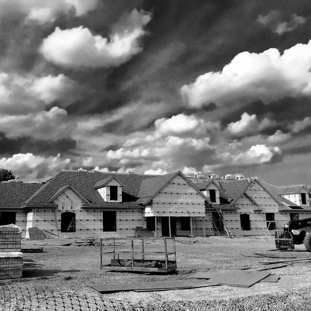 House construction site under a dramatic cloudy sky; unfinished homes.
