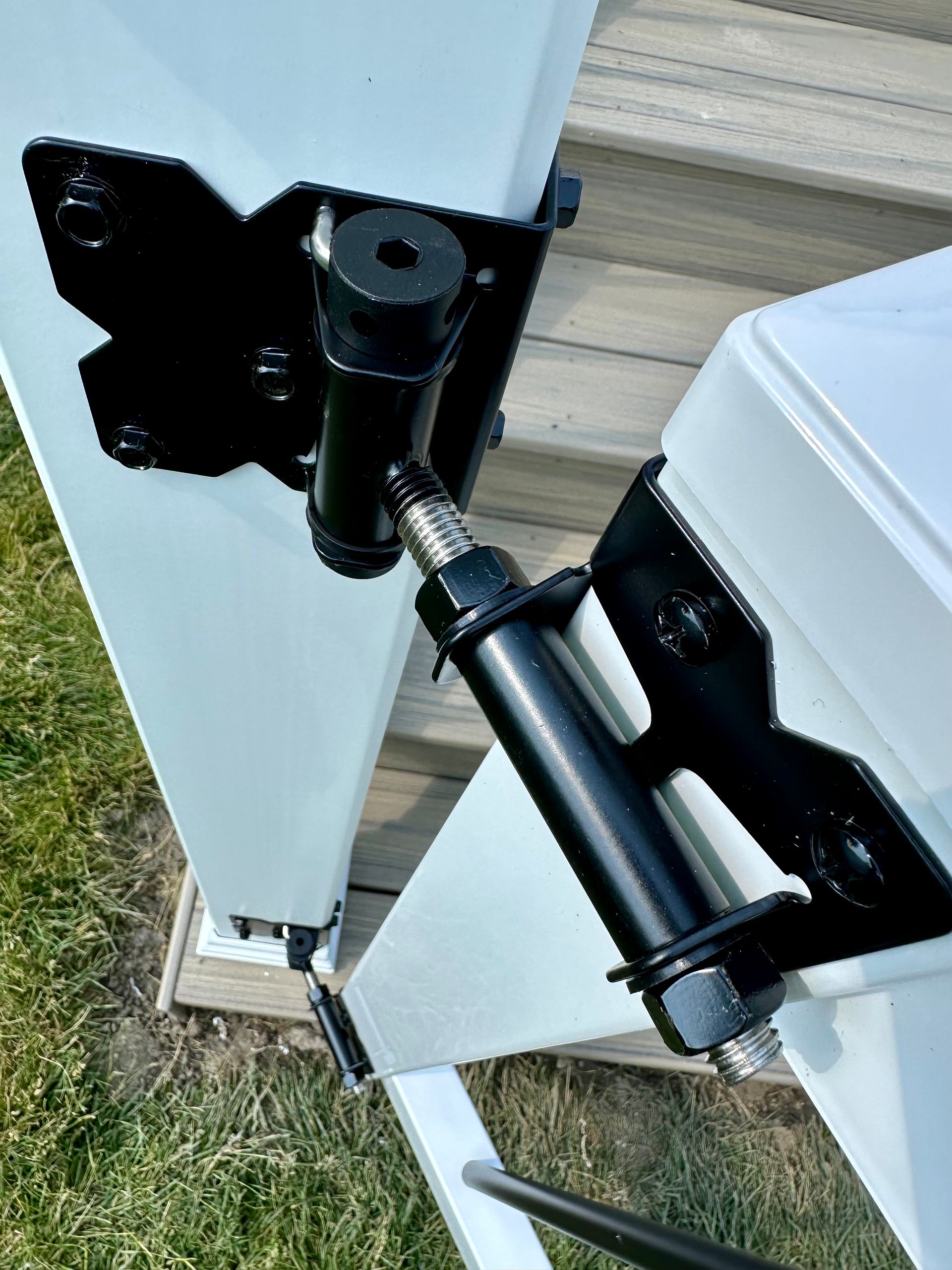 Black gate hinges mounted on white fence post and gate.