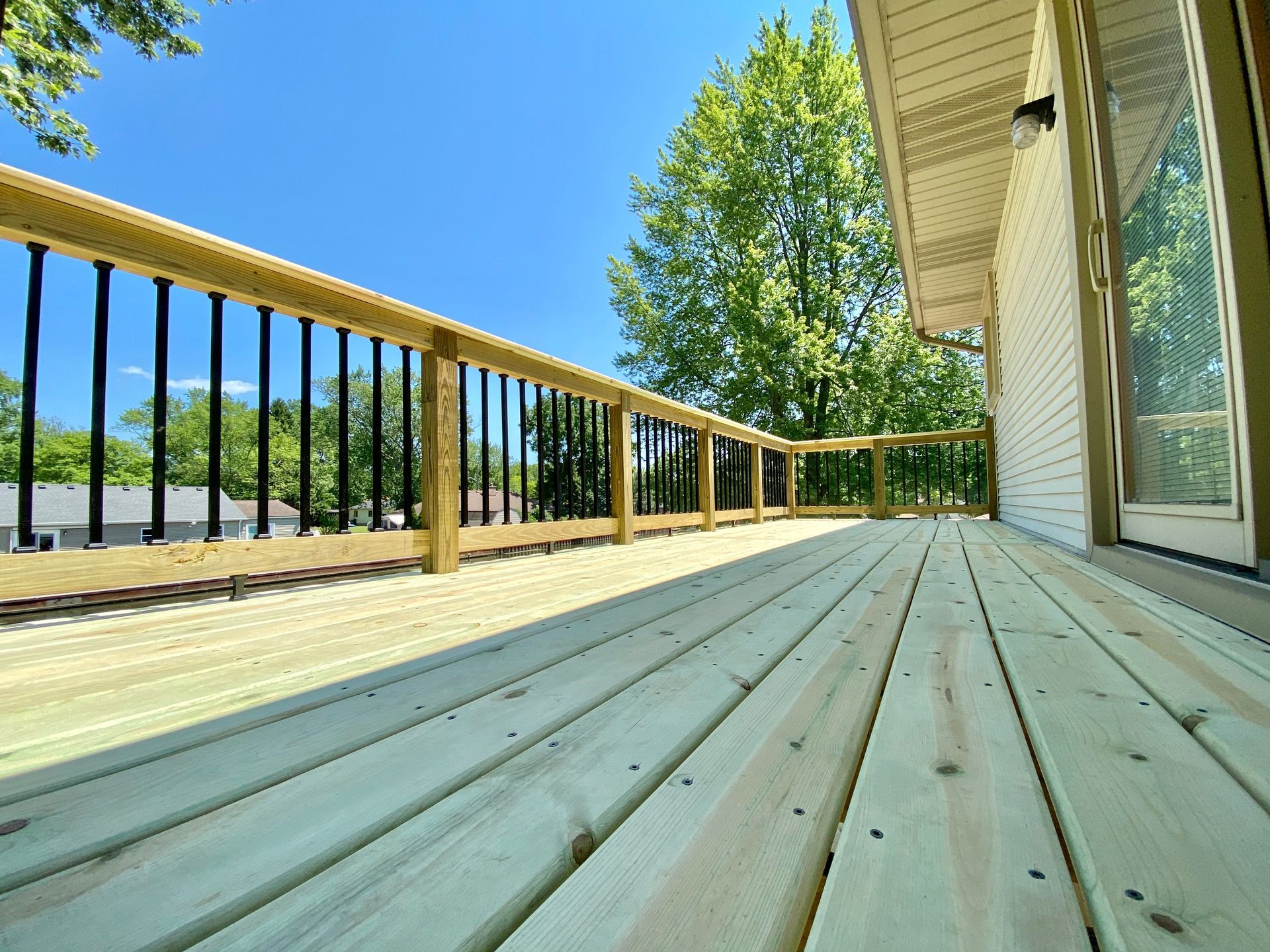 Wooden deck with black railings on a sunny day.
