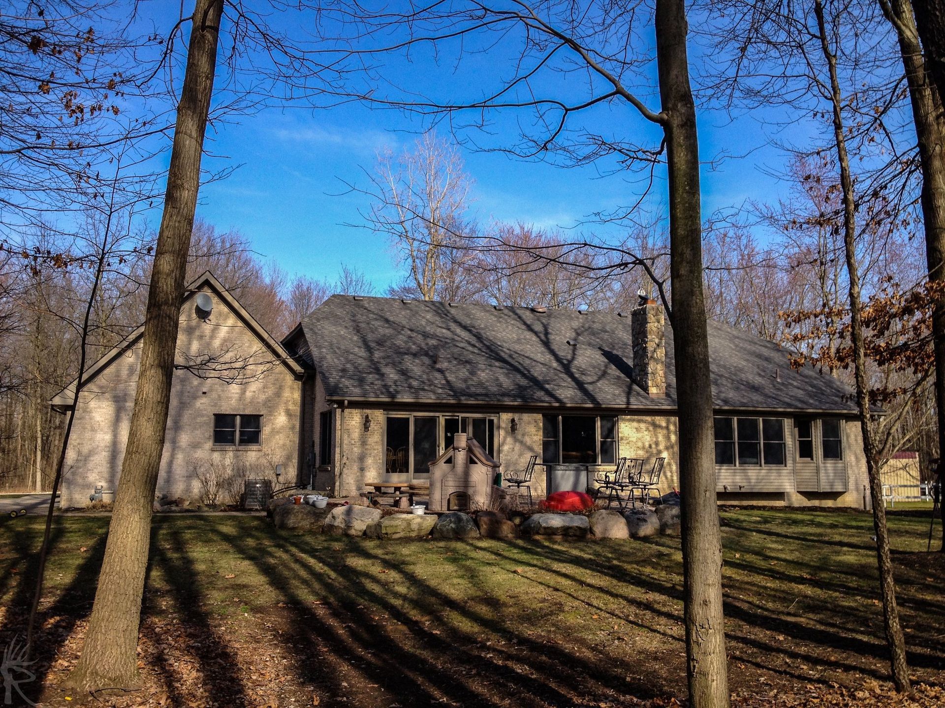 Rustic, wooden house in a forest setting with a gray roof and a few windows.