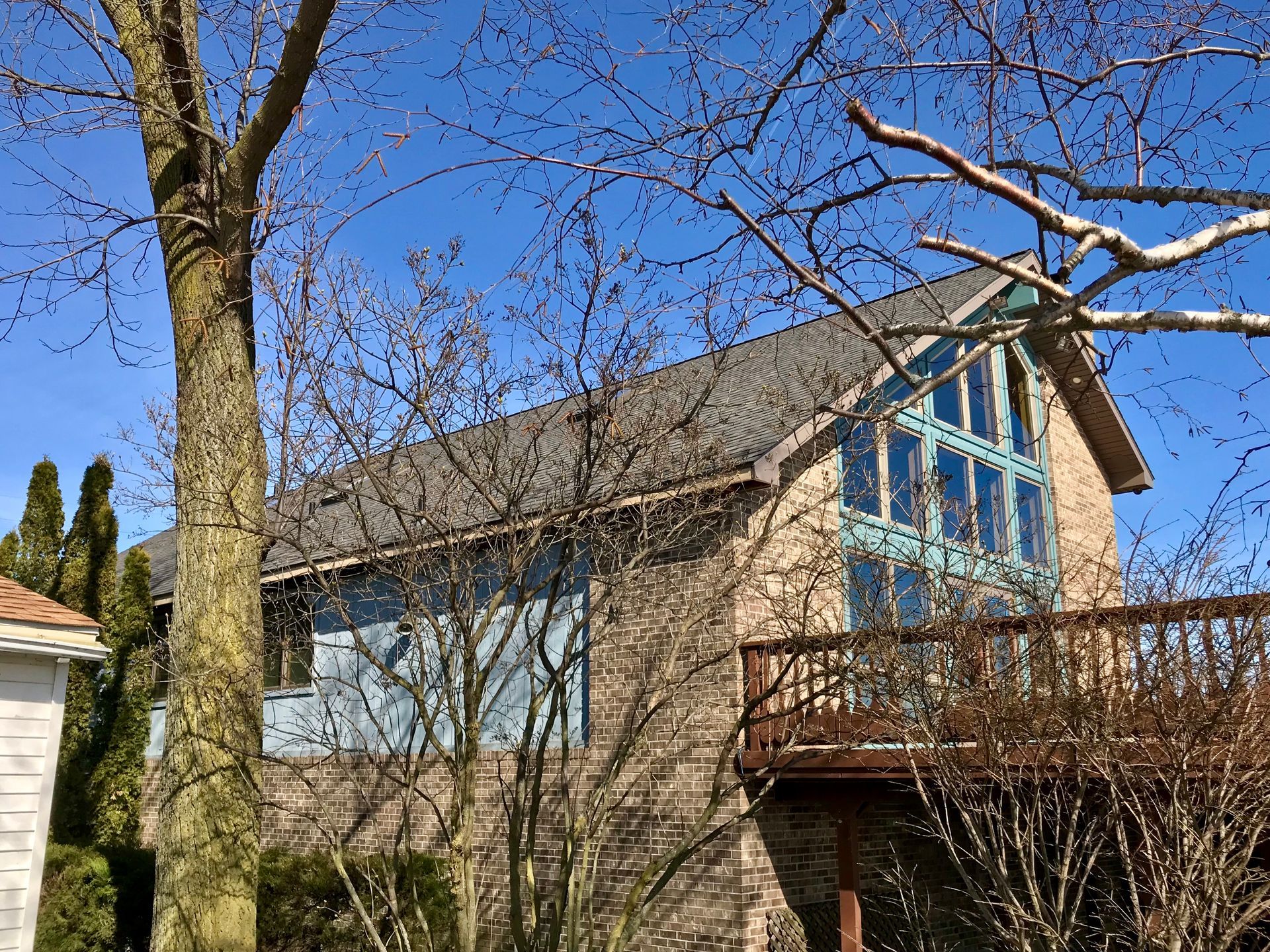 Brick building with deck, large arched window, and tree branches against a clear blue sky.