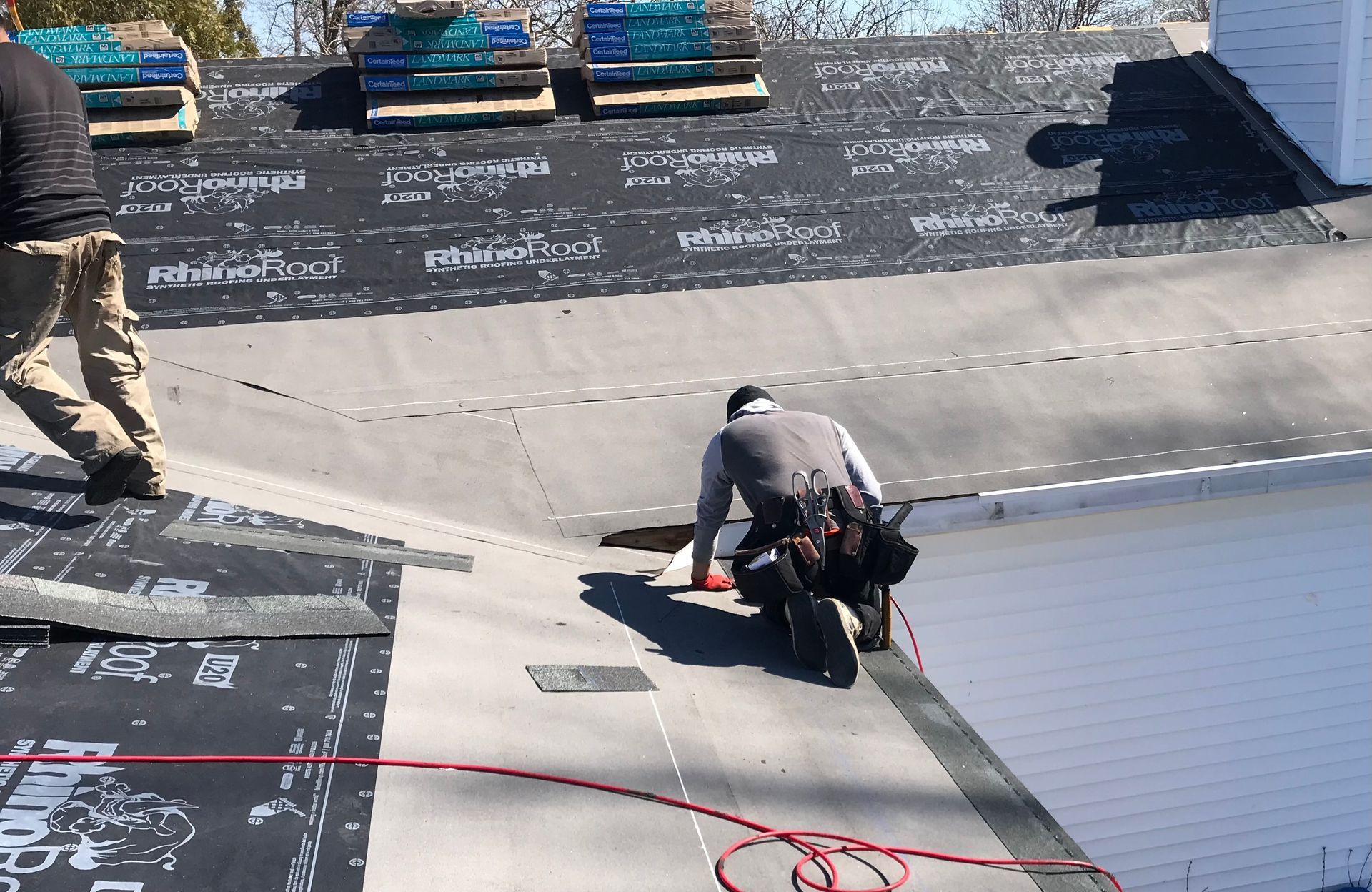 Roofers installing roofing material on a house, sunny day.