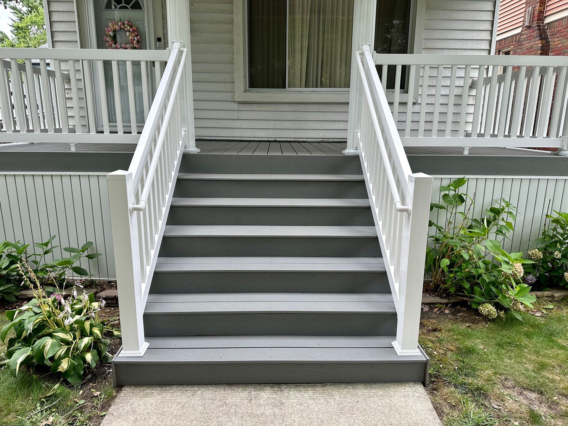 Gray painted steps leading up to a white house with white railings.