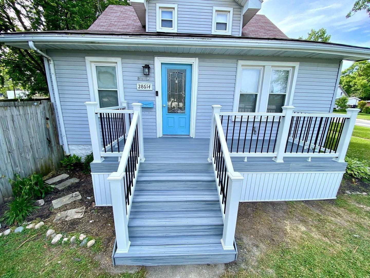 Blue house with gray porch and blue front door. Black and white railing. Number 124 above the door.