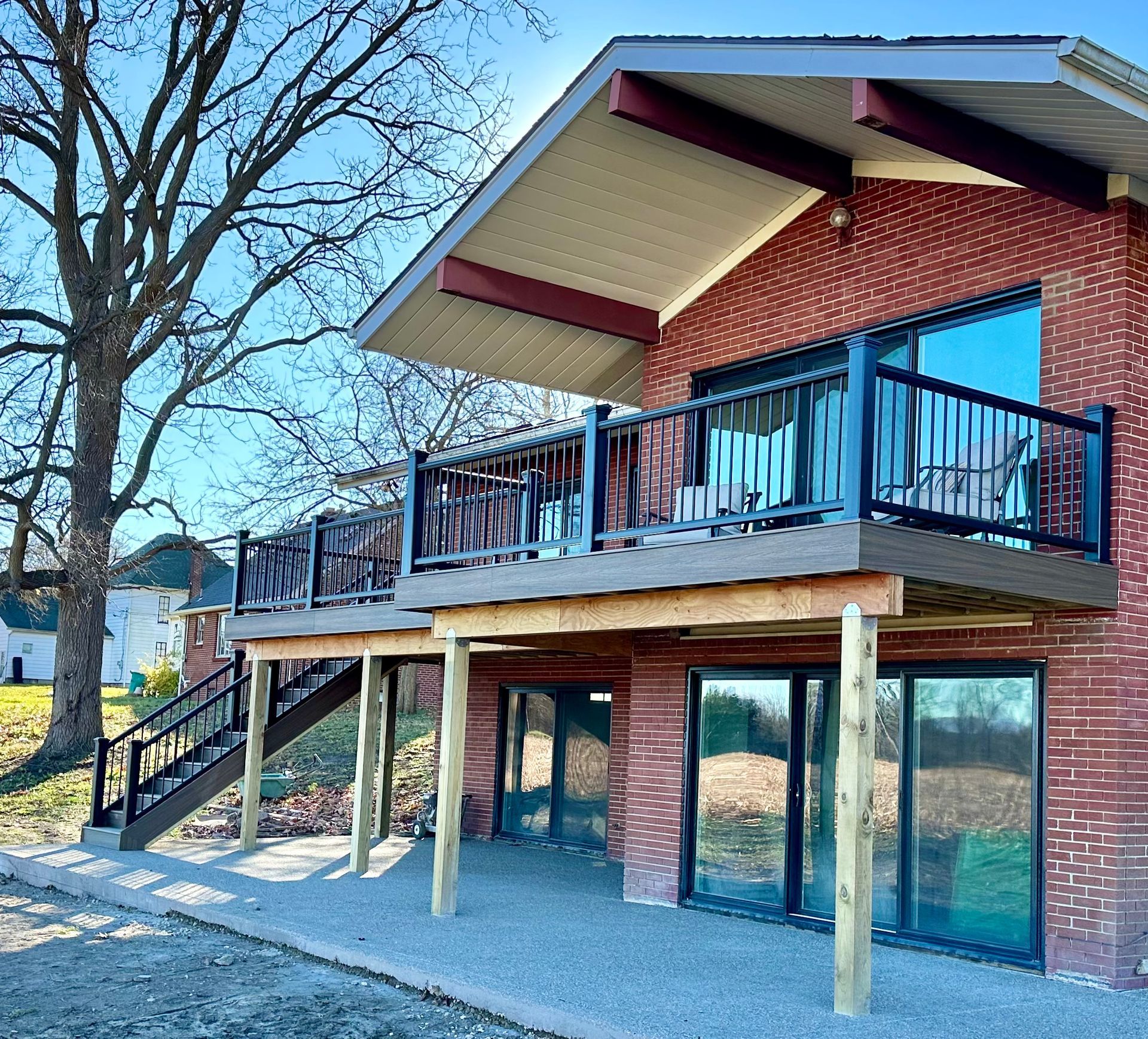 Red brick house with a deck and large windows; wooden posts support the deck.