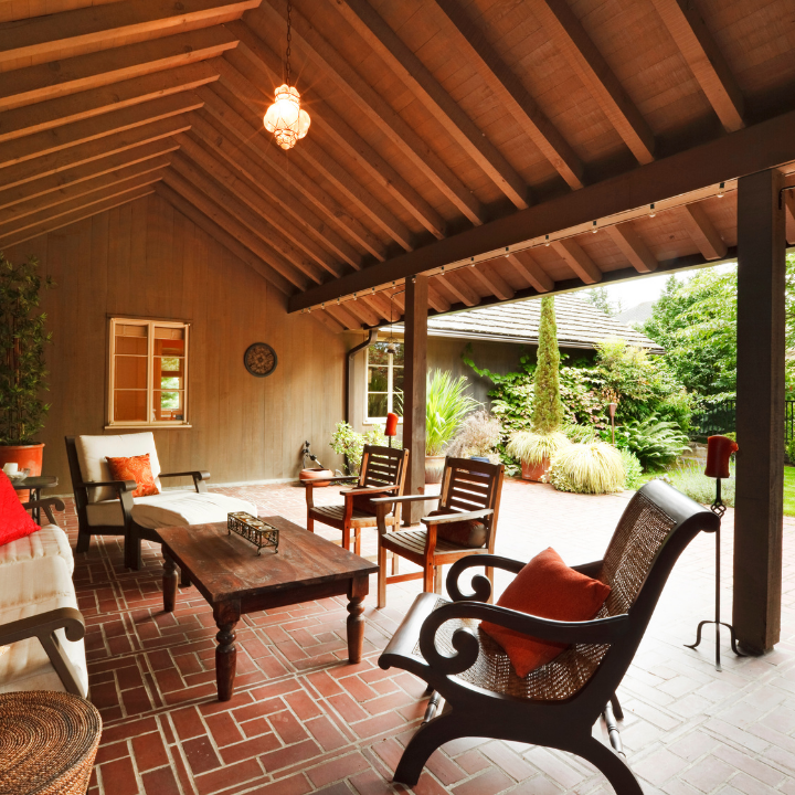 A patio with a couch and chairs under a wooden roof