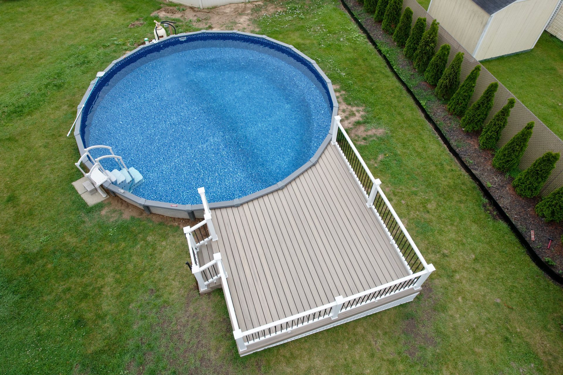 Above-ground pool with attached deck in a grassy backyard.