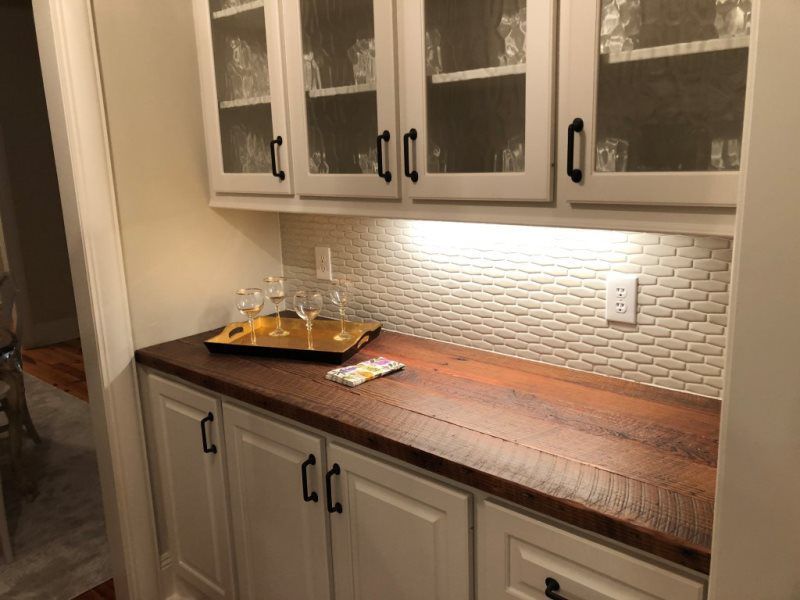 A kitchen with white cabinets and a wooden counter top.