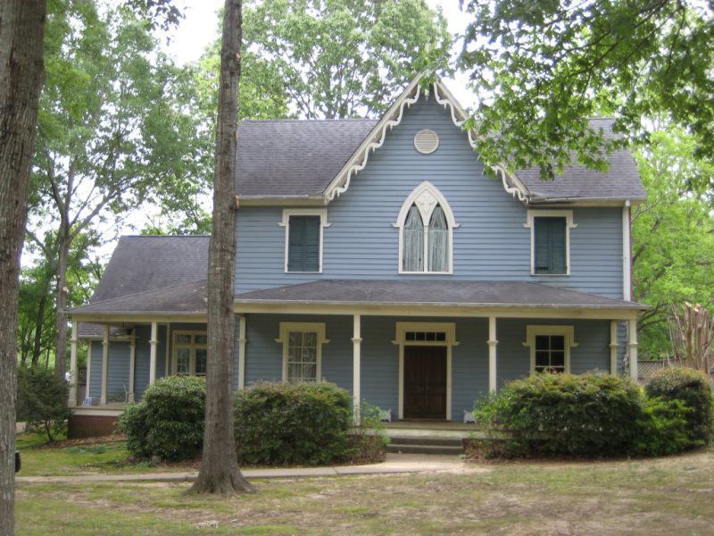 A blue house with a porch and arched windows