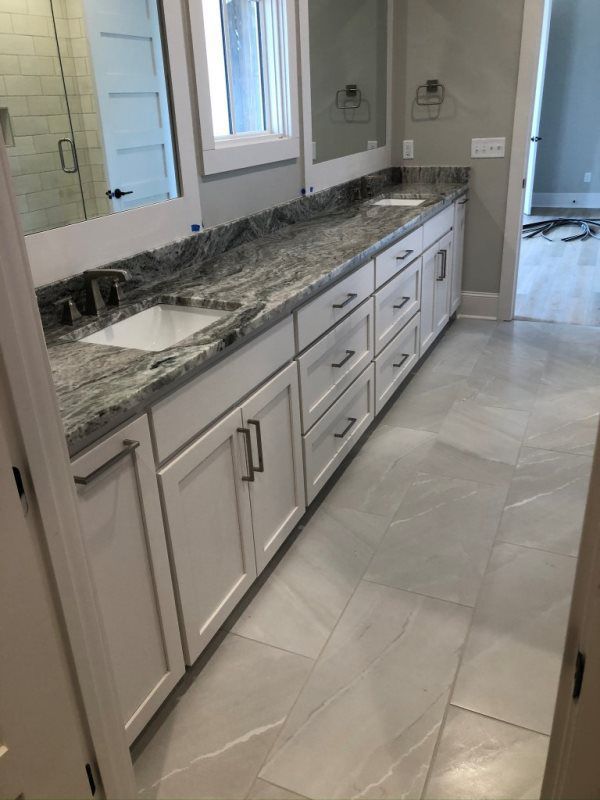 A bathroom with white cabinets and granite counter tops.