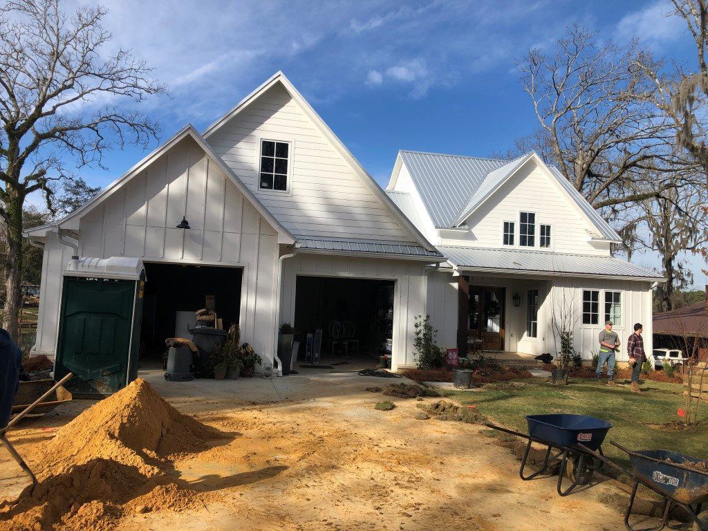 A white house with a green garage door is being built.