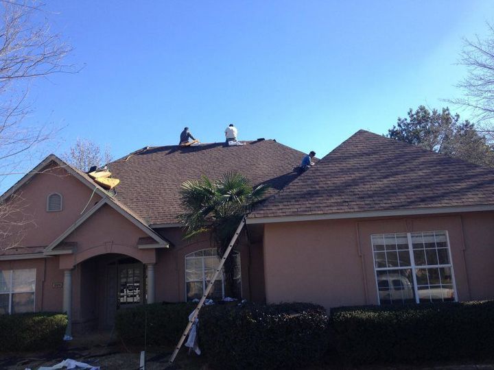 Two men are working on the roof of a house