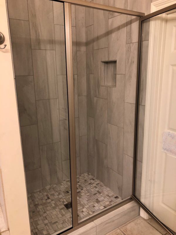 A bathroom with a walk in shower with a glass door.
