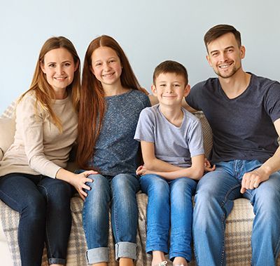 A family is sitting on a couch posing for a picture.