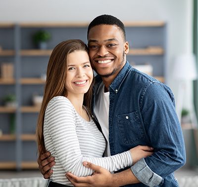 A man and a woman are hugging each other in a living room.