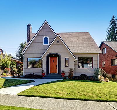 A house with a brown door and a brick house in the background