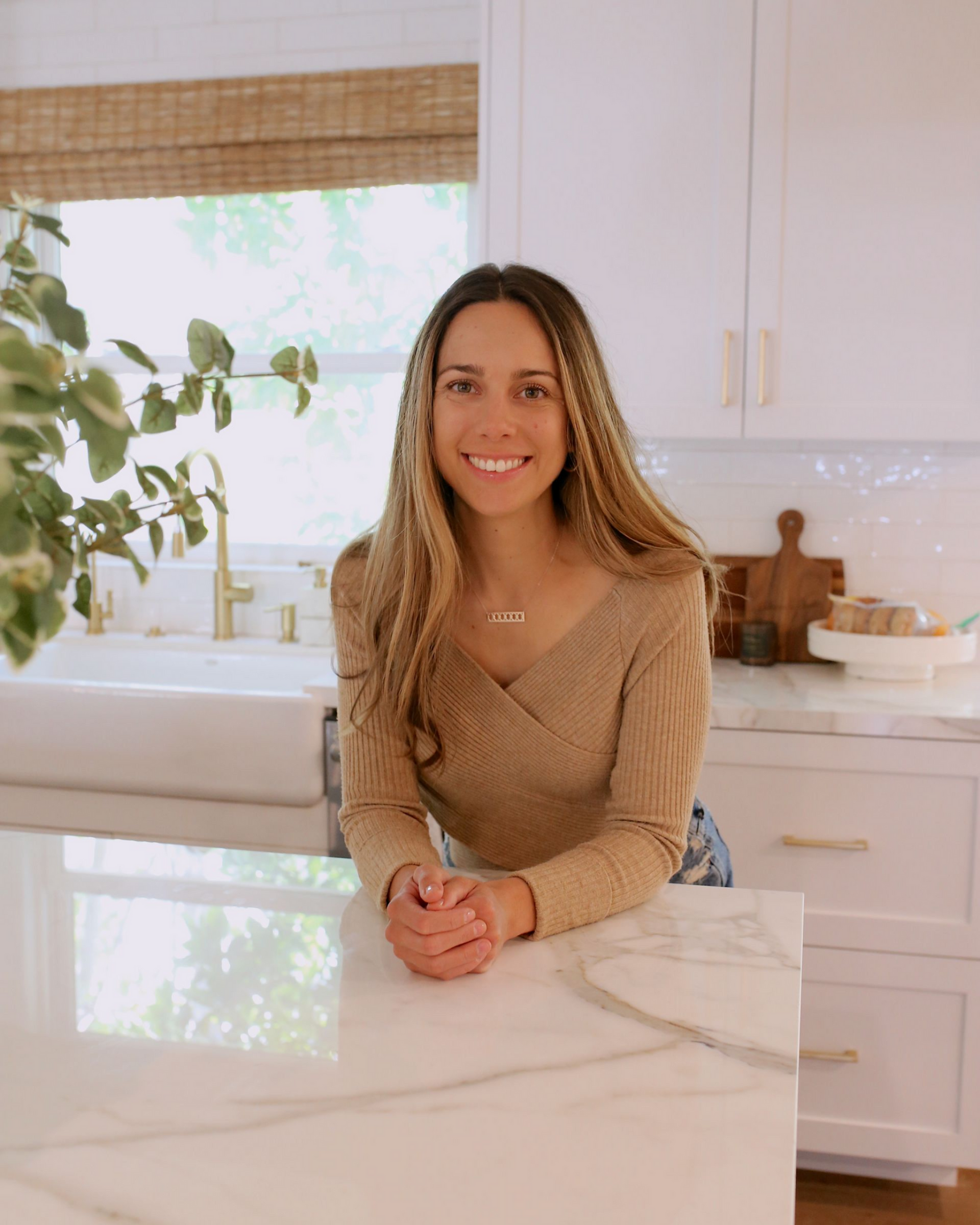 A woman is sitting on a counter in a kitchen.