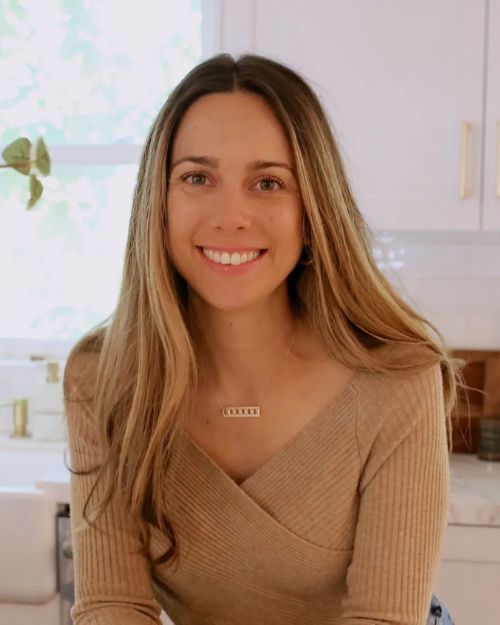 A woman is sitting on a counter in a kitchen.