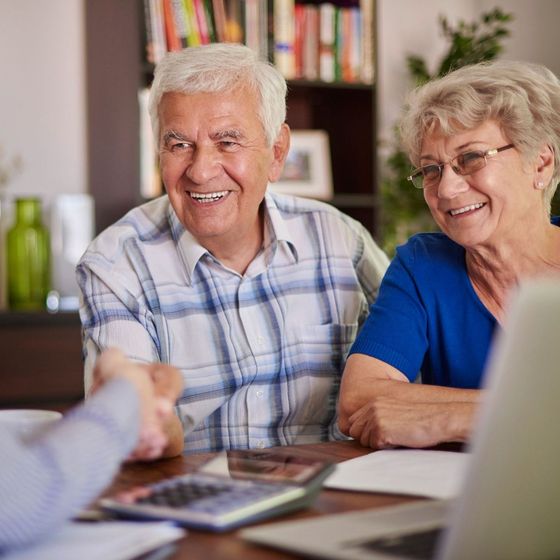 A man and a woman are sitting at a table with a laptop and a calculator.