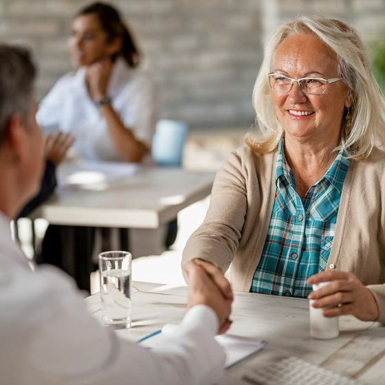 A woman is shaking hands with a man at a table.