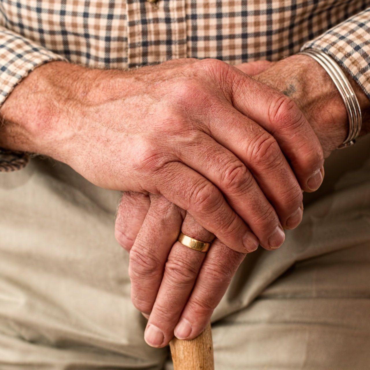 A man with a ring on his finger is holding a cane.