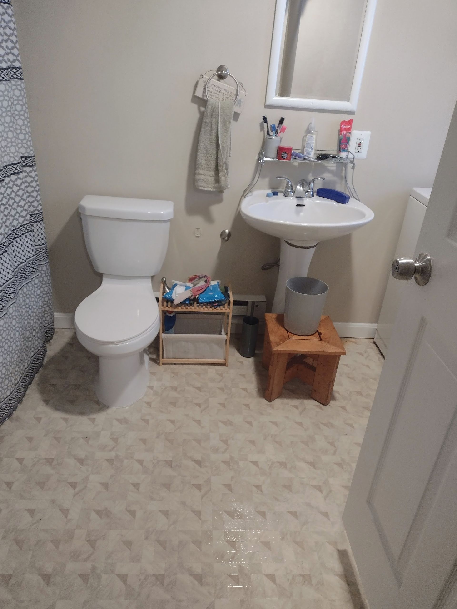 A small bathroom with a toilet, sink, and step stool; tan and white color scheme.