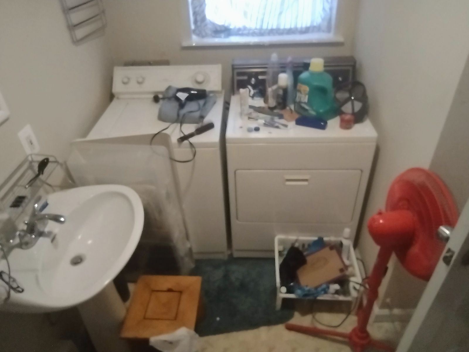 Laundry room with a washing machine, dryer, sink, fan, and miscellaneous items on top.