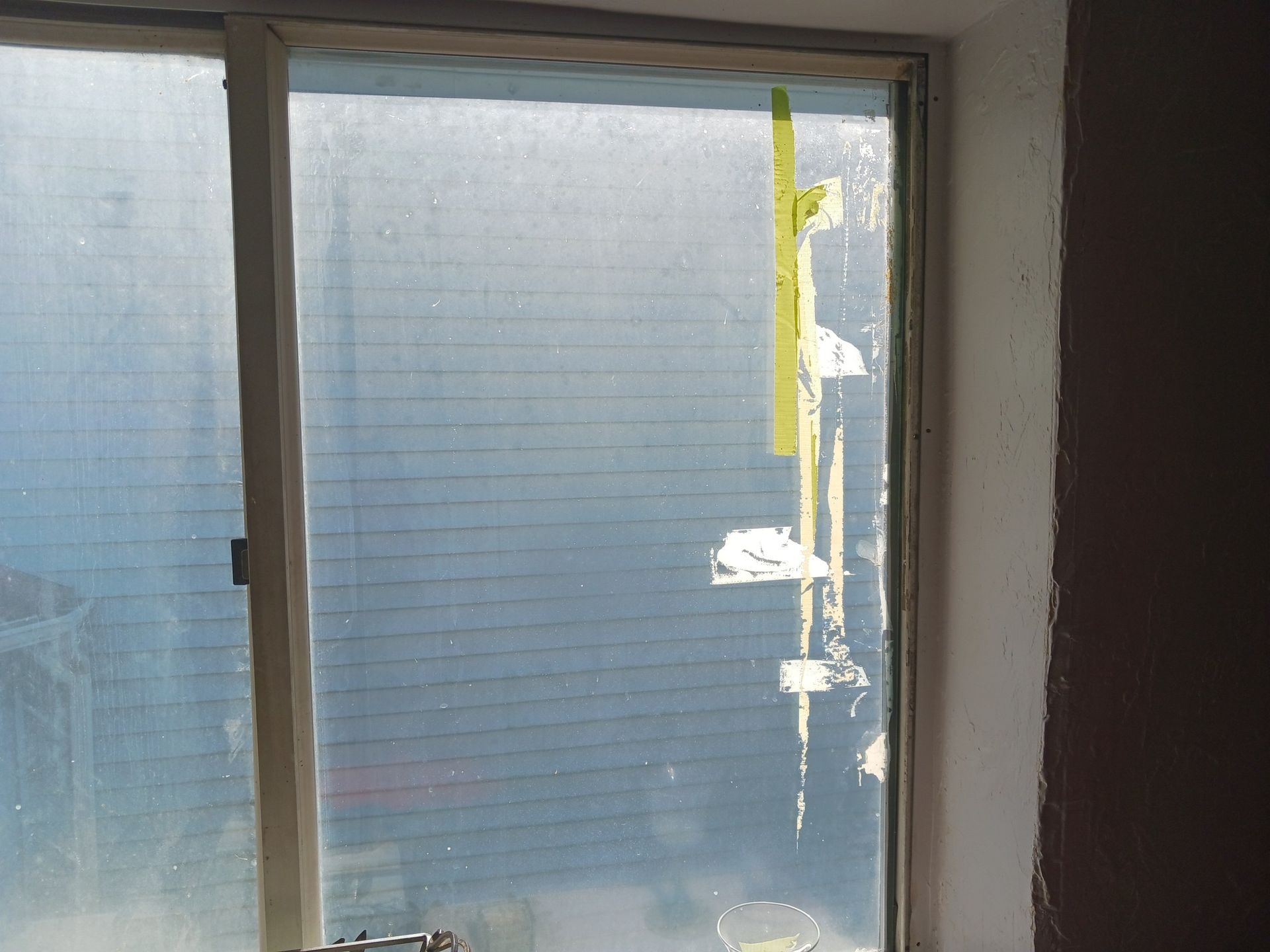 Window with frosted glass, damaged and taped, set in a white frame, indoors.