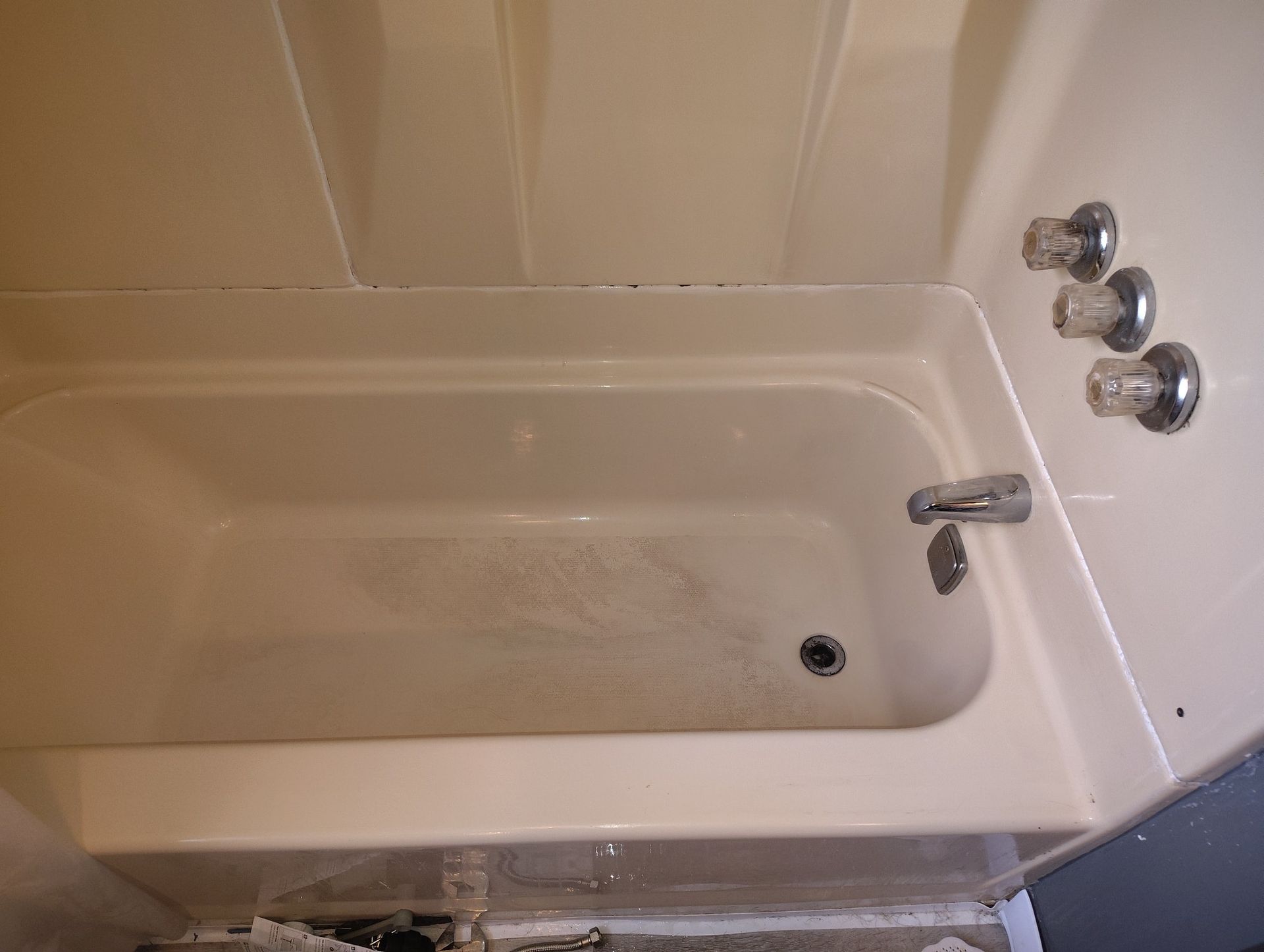Beige bathtub with faucet and three chrome faucet handles on the right.