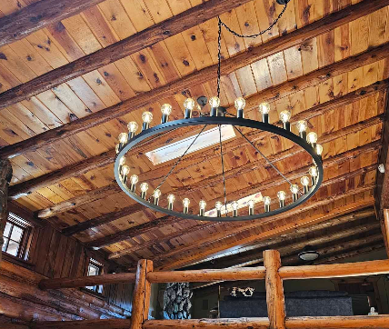 A large chandelier is hanging from the ceiling of a wooden cabin.