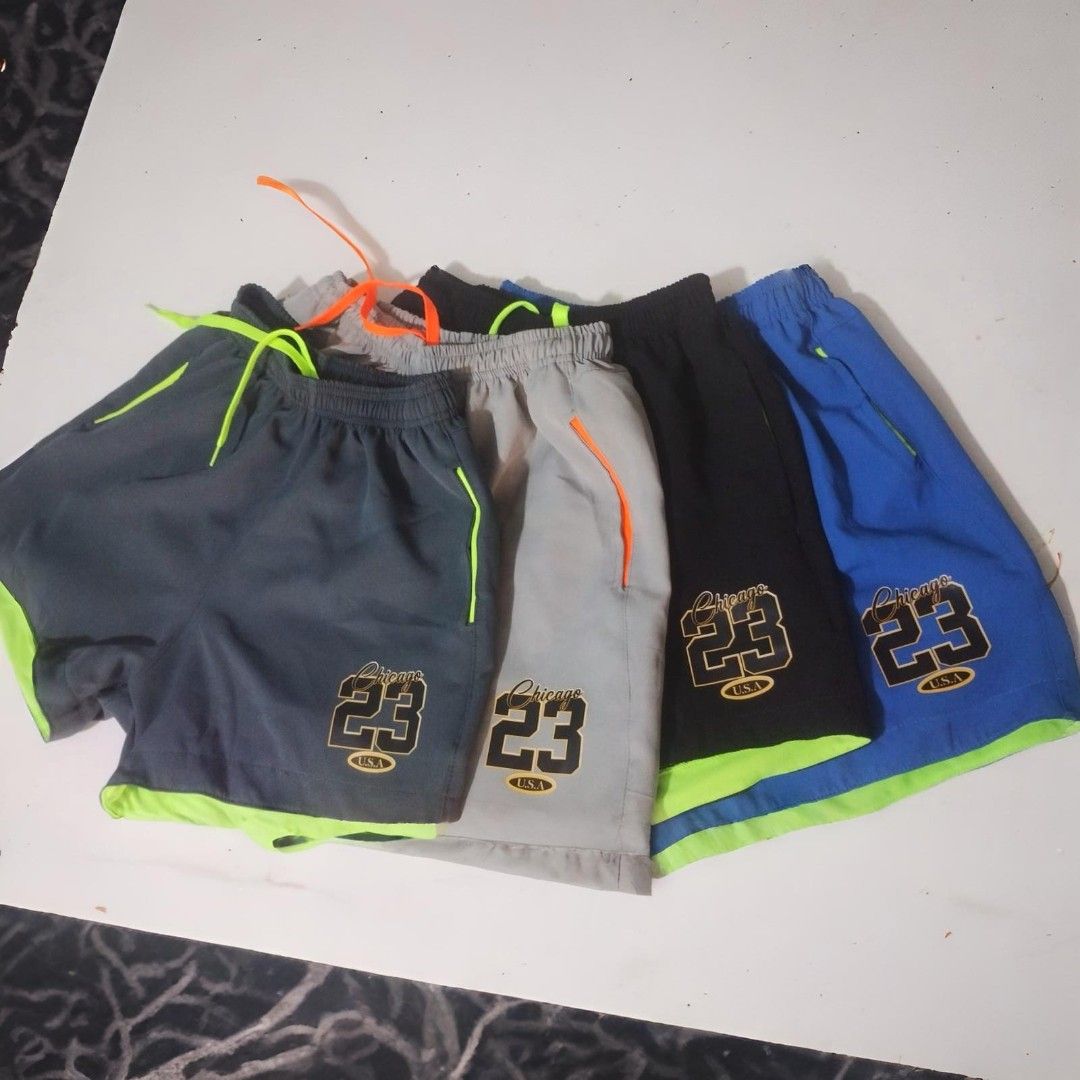 Cinco pares de pantalones cortos deportivos: azul marino, gris, negro y azul con ribete verde neón.