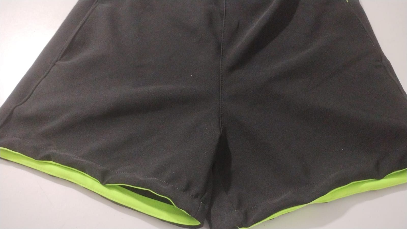 Cuatro pares de pantalones cortos deportivos en azul, negro, verde.