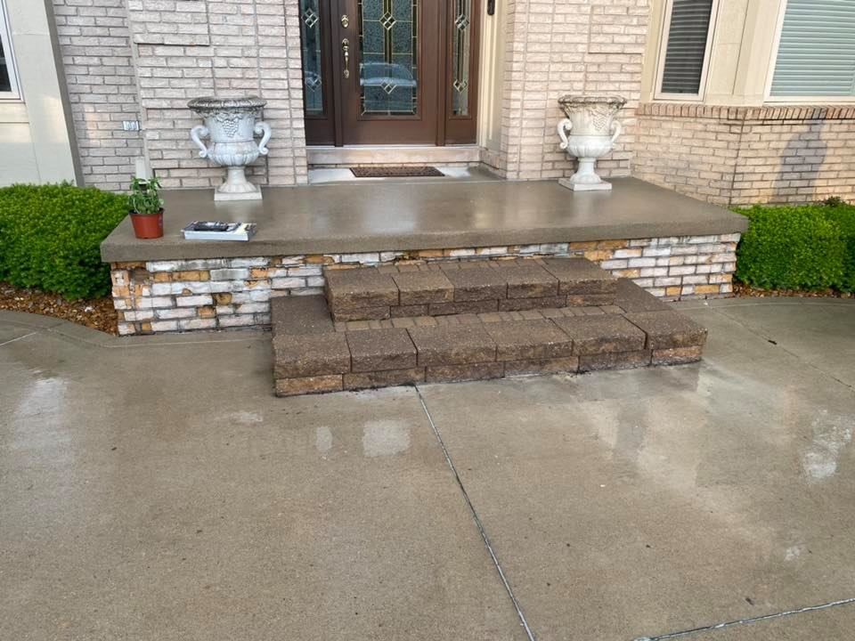 A brick house with a concrete porch and steps