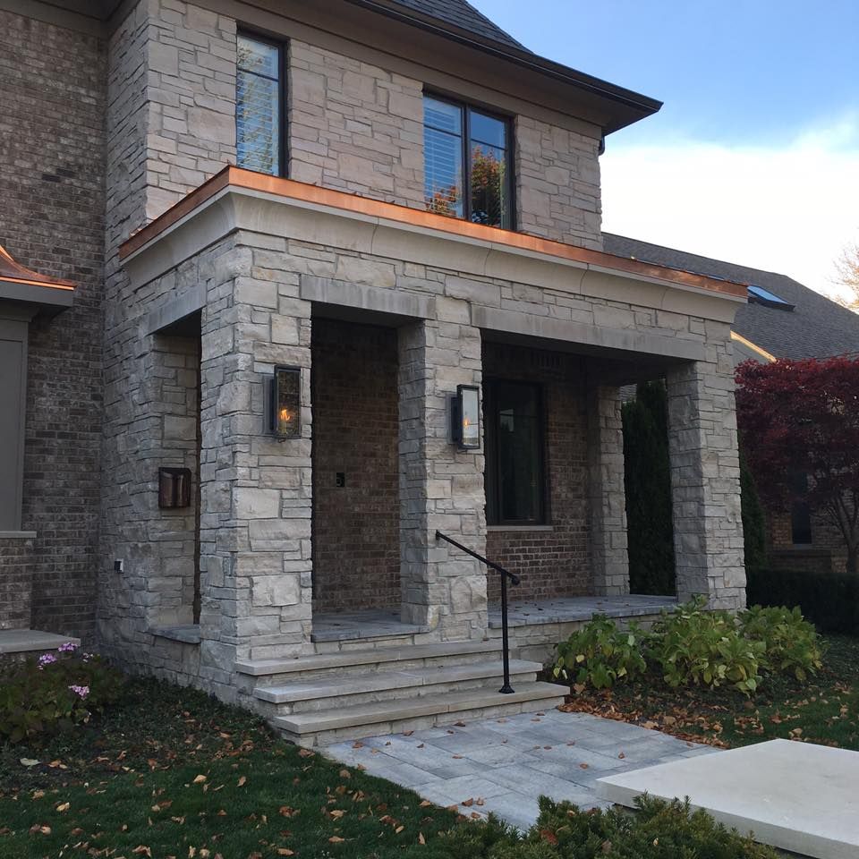 A large brick house with a porch and a copper roof