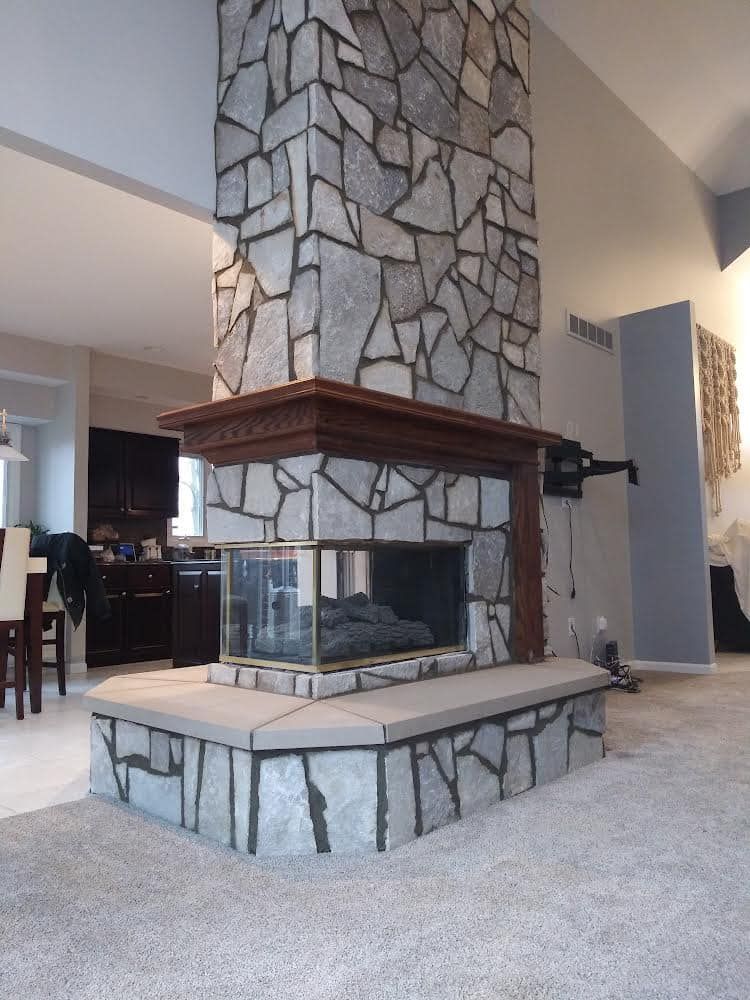 A living room with a stone fireplace in the middle