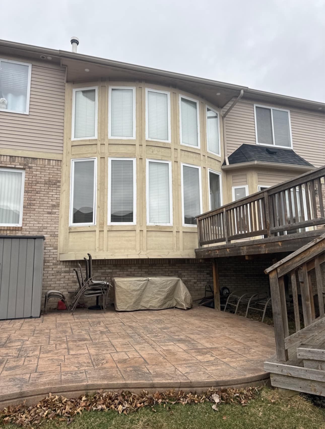 The back of a house with a large deck and a lot of windows.