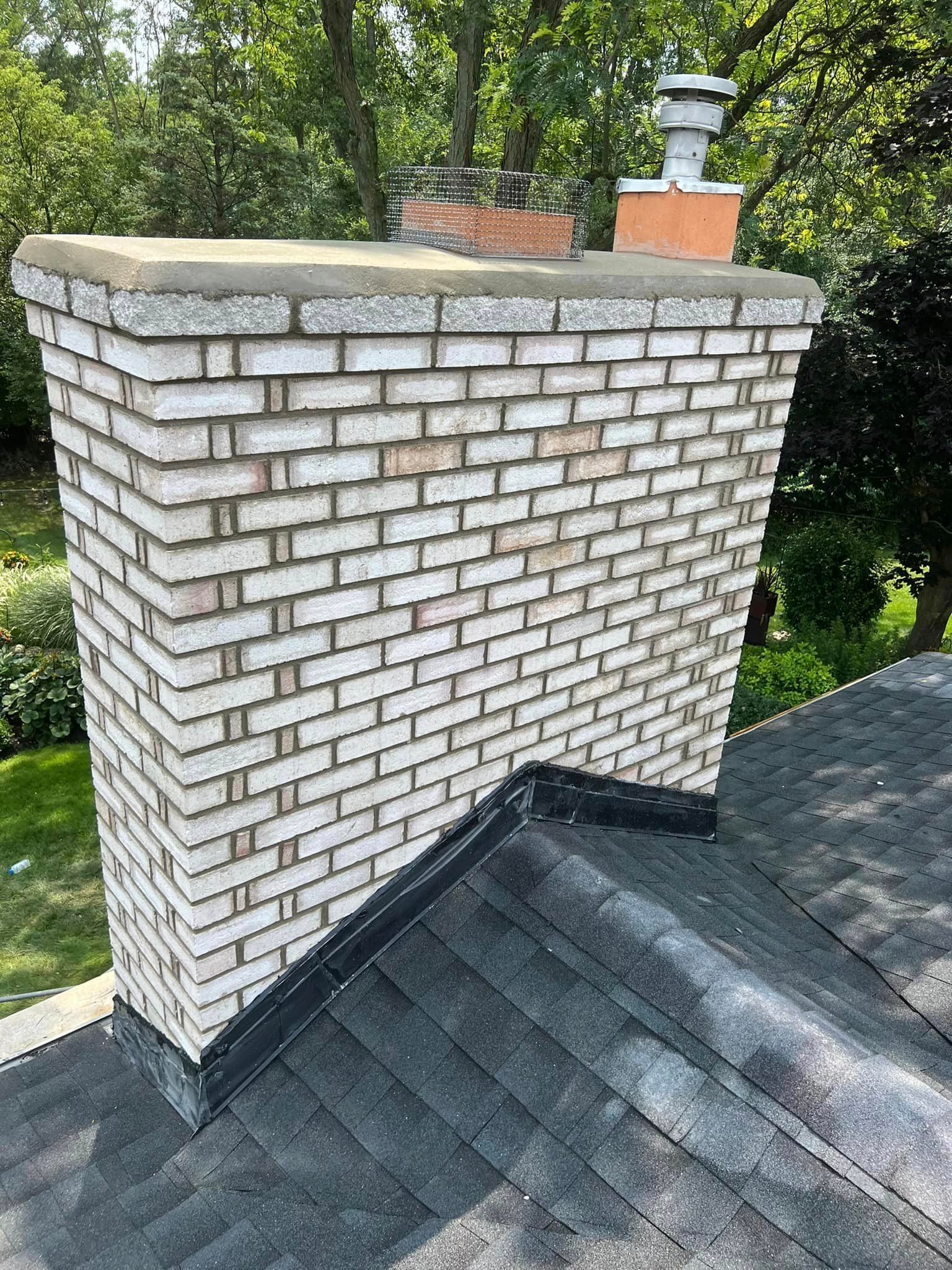 A brick chimney is on the roof of a house.