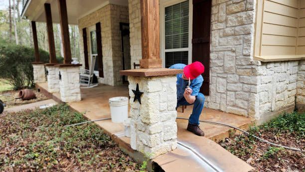 Worker putting finishing touches on the column caps of columns on front porch of home.