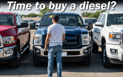 A man is looking at a diesel truck in a parking lot.
