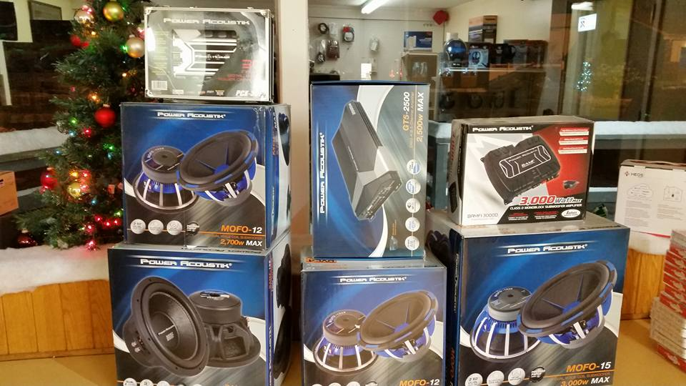 A bunch of speakers are stacked on top of each other in front of a christmas tree.