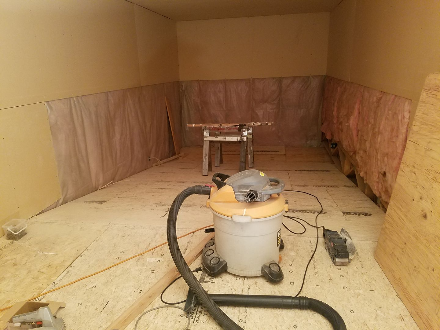 A vacuum cleaner is sitting on the floor of a room under construction.