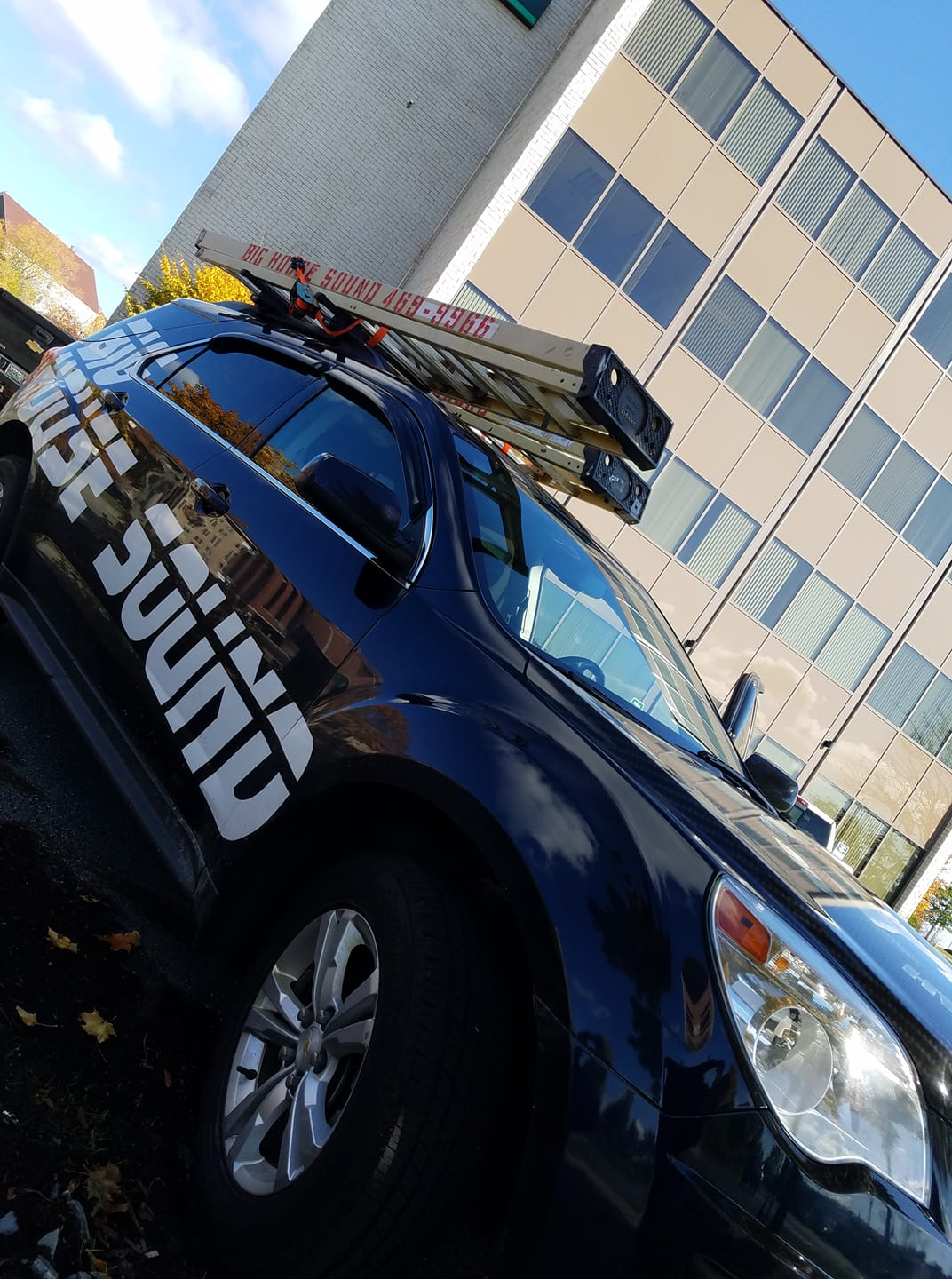 A black car with the word sound on the side is parked in front of a building