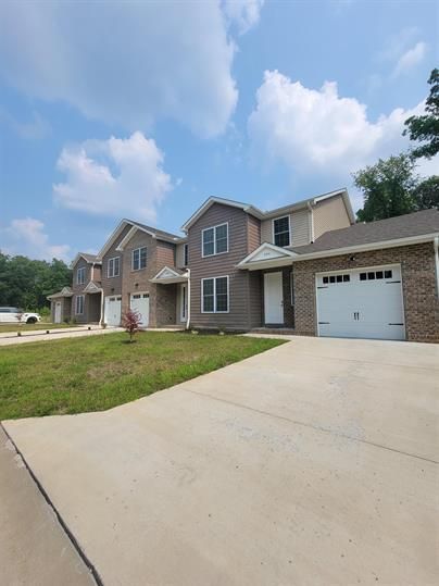 A row of houses with a concrete driveway in front of them