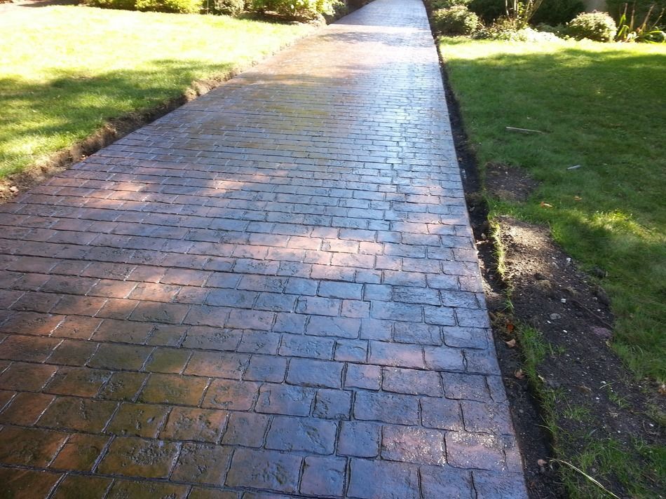 A brick walkway going through a lush green field